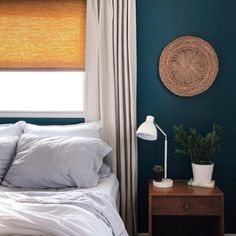 a bedroom with blue walls and white linens on the bed, along with a wicker basket