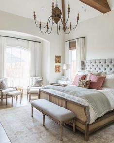 a bedroom with a large bed, chandelier and two chairs in the corner