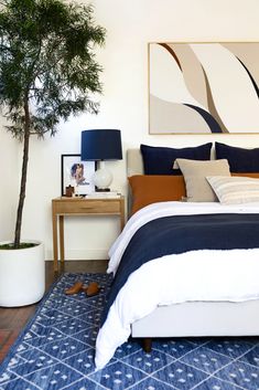 a bedroom with blue and white bedding next to a potted plant