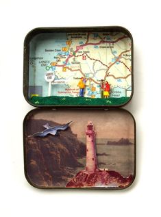 two tins with magnets in them on top of a white surface, one has a lighthouse and the other has a map