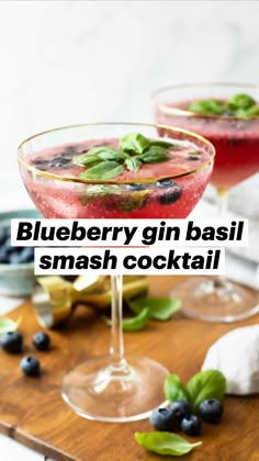 two wine glasses filled with blueberries and mint garnish on a cutting board