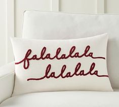 a white couch with a red embroidered pillow that says falabella dalba on it