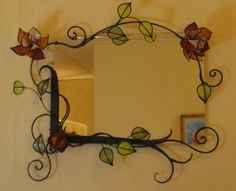 a mirror that is on the wall with vines and flowers painted on it's sides