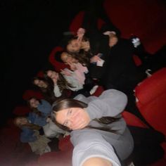 a group of people sitting on top of red seats in a movie theater with their hands up