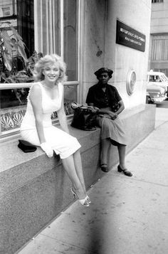 a woman sitting on the ledge of a building next to a man