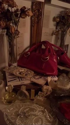 a red purse sitting on top of a table covered in glass plates and vases