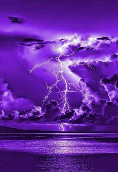 a purple sky filled with lots of clouds next to the ocean under a lightning bolt