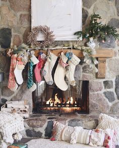 a fireplace with stockings hanging from it's mantle next to pillows and other decorations