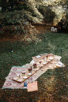 an outdoor picnic is set up in the grass with plates and utensils on it