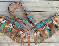 a leather belt with feathers and beads on the front, sitting on a wooden surface