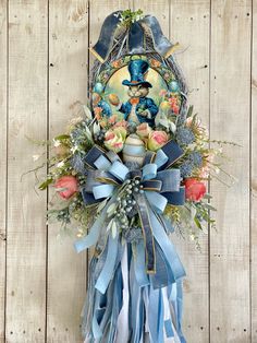 a blue and white wreath hanging on the side of a wooden wall with flowers in it