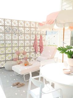 a white table and chairs with umbrellas on top of it in front of a wall