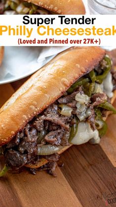 two sandwiches with meat, peppers and onions on a wooden table next to a glass of water