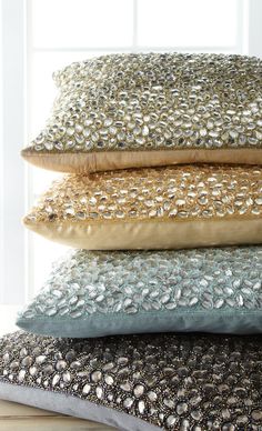 four pillows stacked on top of each other in different colors and sizes, all with sequins