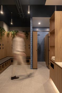 a blurry photo of a person walking in a room with wooden cabinets and benches