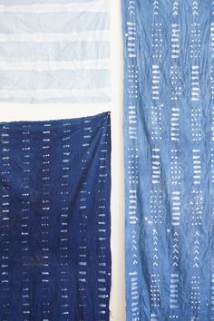 two pieces of blue and white fabric hanging on the wall next to each other,