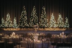 the tables are set with white linens and lit trees