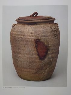 an old clay pot with a lid and handle on the side, sitting in front of a white background