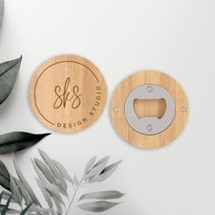 two wooden bottle openers with the word design studio engraved on them next to some leaves