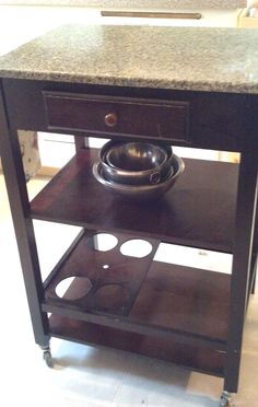 a kitchen cart with a bowl on top and two plates on the shelf below it