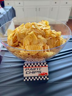 a bowl filled with yellow chips sitting on top of a blue tablecloth covered table