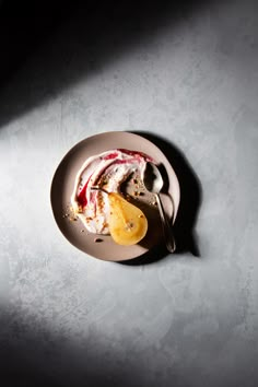 a white plate topped with fruit and yogurt on top of a gray table