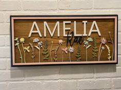 a wooden sign that says amella with flowers on it