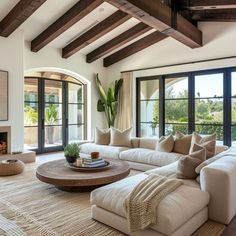 a living room with couches, tables and large windows