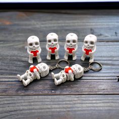 five skeleton keychains with red bow ties on top of a wooden table next to keys