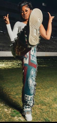 a woman in white shirt and black pants holding up a pair of shoes on grass