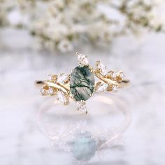 a green and white stone ring sitting on top of a table next to some flowers