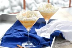 two glasses filled with dessert sitting on top of a table