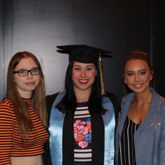 three young women in graduation gowns posing for a photo with one woman wearing a cap and gown