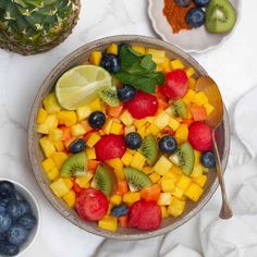 a bowl filled with fruit next to bowls of blueberries, kiwis and strawberries