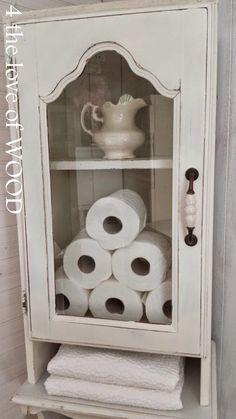 an old china cabinet with rolls of toilet paper in it