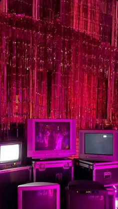 there are many tvs and television sets in the room with purple lights hanging from the ceiling