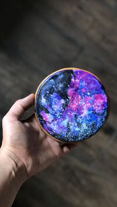 a hand holding up a purple and blue plate with stars on it's surface