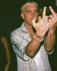 a man making the peace sign with his hand while holding a glass in front of him