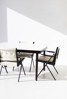 two chairs and a table in front of a white wall