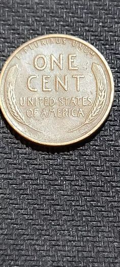 a one cent coin sitting on top of a black cloth covered surface with the words, united states of america