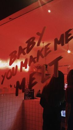 people standing in front of a red wall with writing on it that says, baby me you make me melt