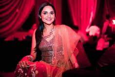 a woman sitting on a couch in a room with red curtains and lights behind her