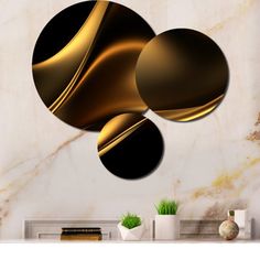 three circles on a wall with gold and black designs in the middle, against a marble background