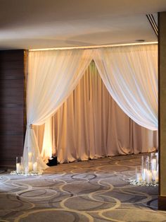 a room that has some candles on the floor in front of it and curtains over the door