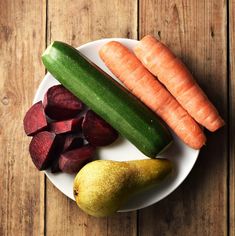 carrots, beets and squash on a white plate with a wooden table in the background