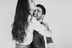 a man and woman are laughing while they hold each other's neck around their shoulders