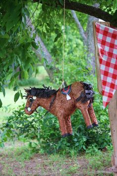 a horse ornament hanging from a tree with a checkered tablecloth on it