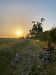 two people sitting in the grass next to their bikes