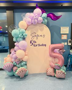 a birthday sign with balloons and mermaid tail