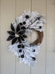 a wreath with black and white flowers hanging on a door